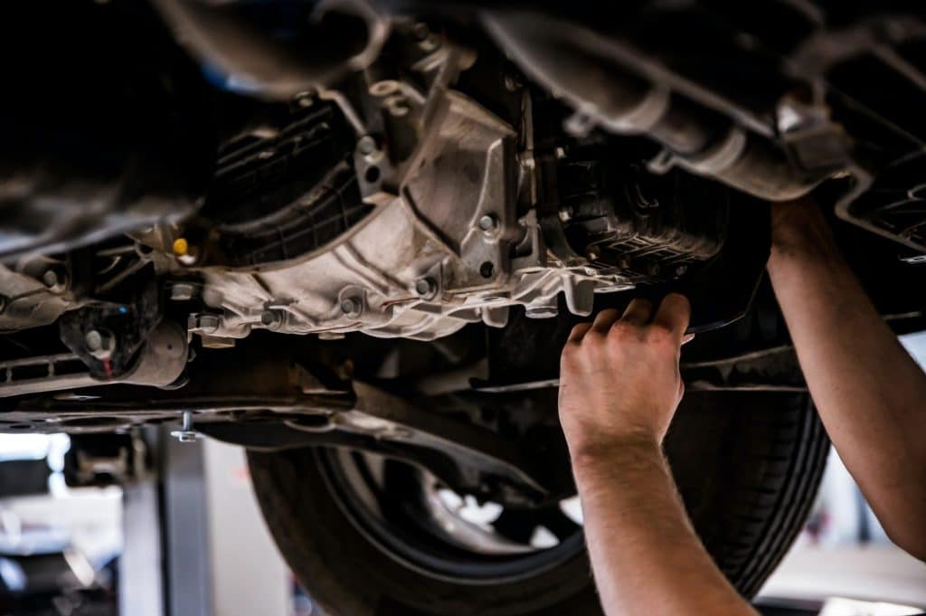 Close up of a mechanic hands repaires lifted car